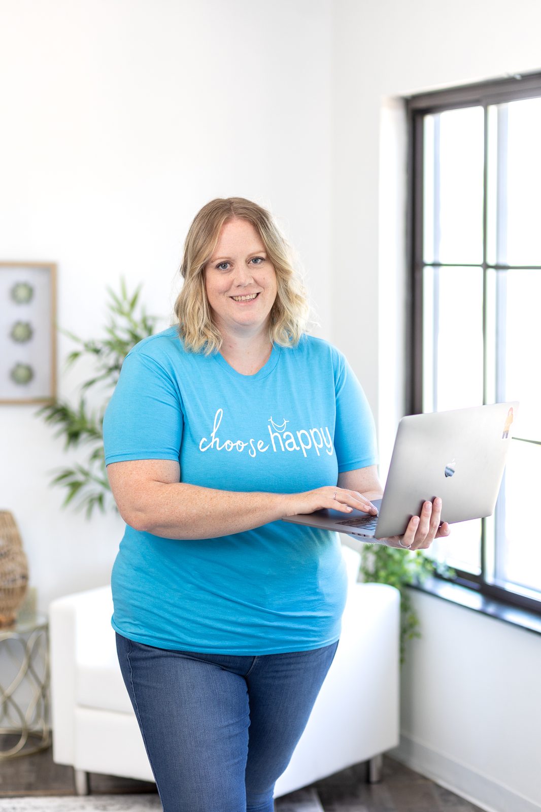 Jen Sanders smiling and holding her laptop, ready to work with you